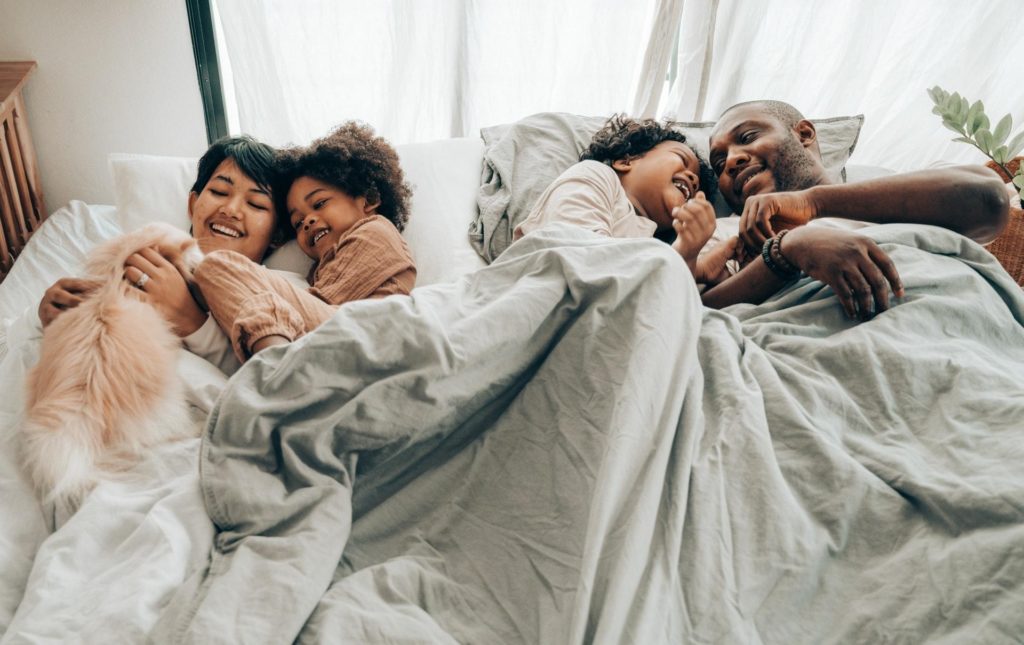 A family laying in bed together smiling and laughing