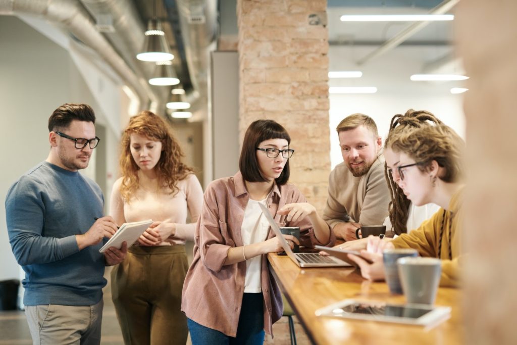 Group of coworkers gathered around the breakfast bar, having a morning meeting