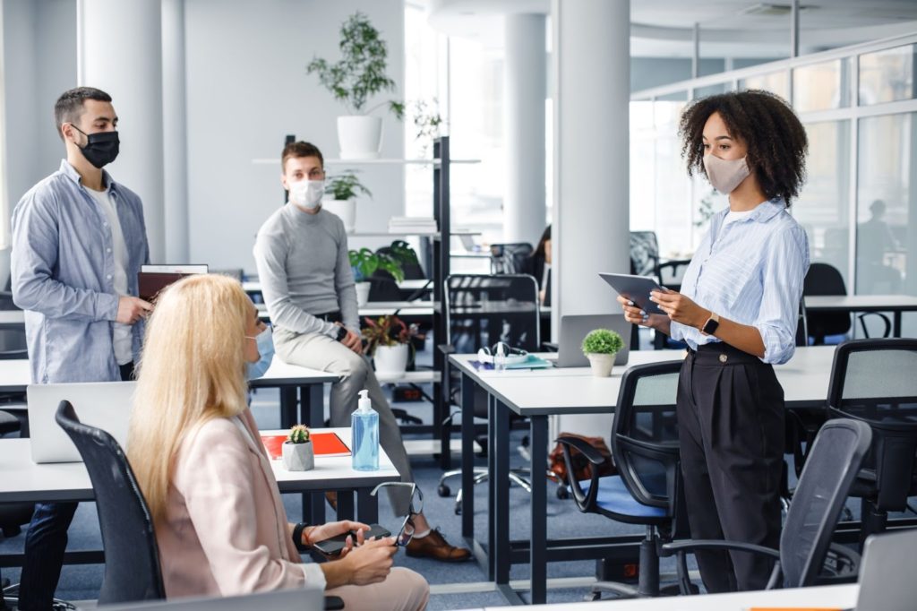 Group of male and female coworkers holding a meeting in an open workspace