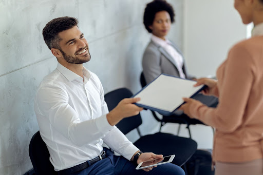 5-Skills-Job-Applicants-Need Smiling man handing back a job application