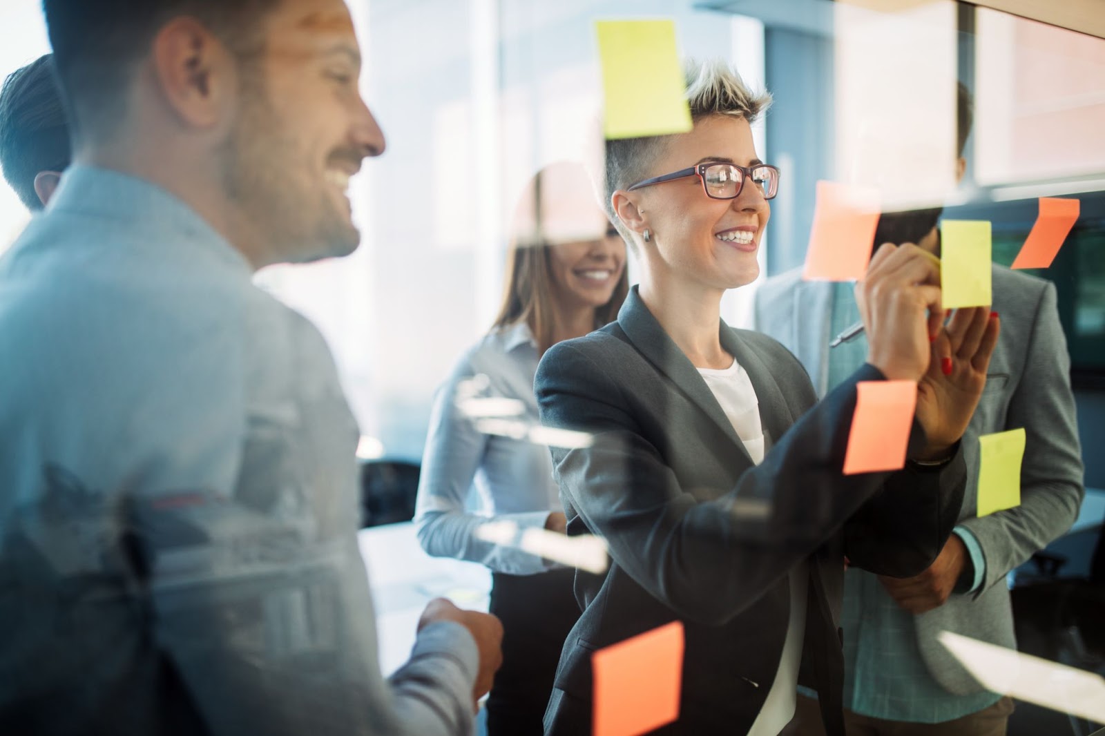 Business woman writing something on a post-it note during a meeting