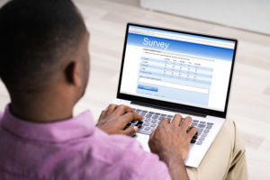 Man Giving Online Survey On Laptop At Home