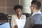 Beautiful female employee in suit is smiling during the job interview. Job applicants having interview. View of a Young attractive woman during job interview