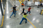 a-group-of-masked-men-and-women-working-in-a-massive-fulfillment-center-doing-gentle-stretching-exercises-to-ensure-the-health-and-wellbeing-of-the-employees-stockpack-gettyimages