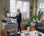 life-in-time-of-covid-19-mature-woman-working-on-computer-from-home-at-the-stand-up-desk-she-has-long-grey-hair-and-dressed-in-casual-black-outfit-interior-of-living-room-set-up-with-home-office-stati-stockpack-gettyimages
