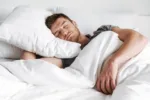 Handsome young man sleeping in bed at home