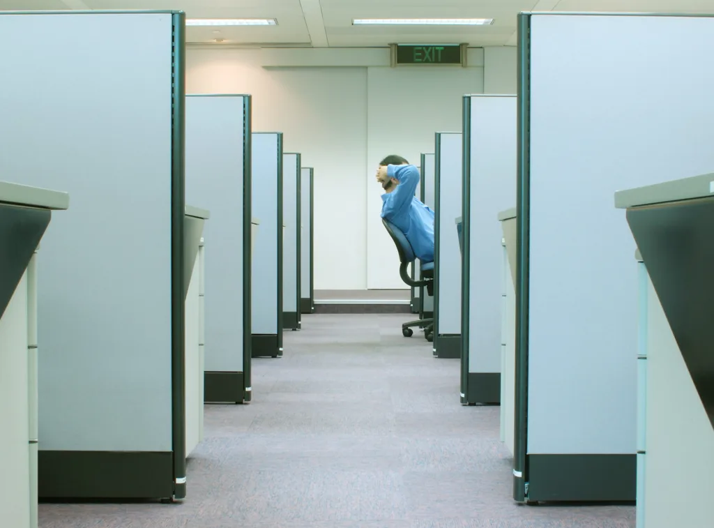 man reclining on his chair in cubicle with EXIT sign above