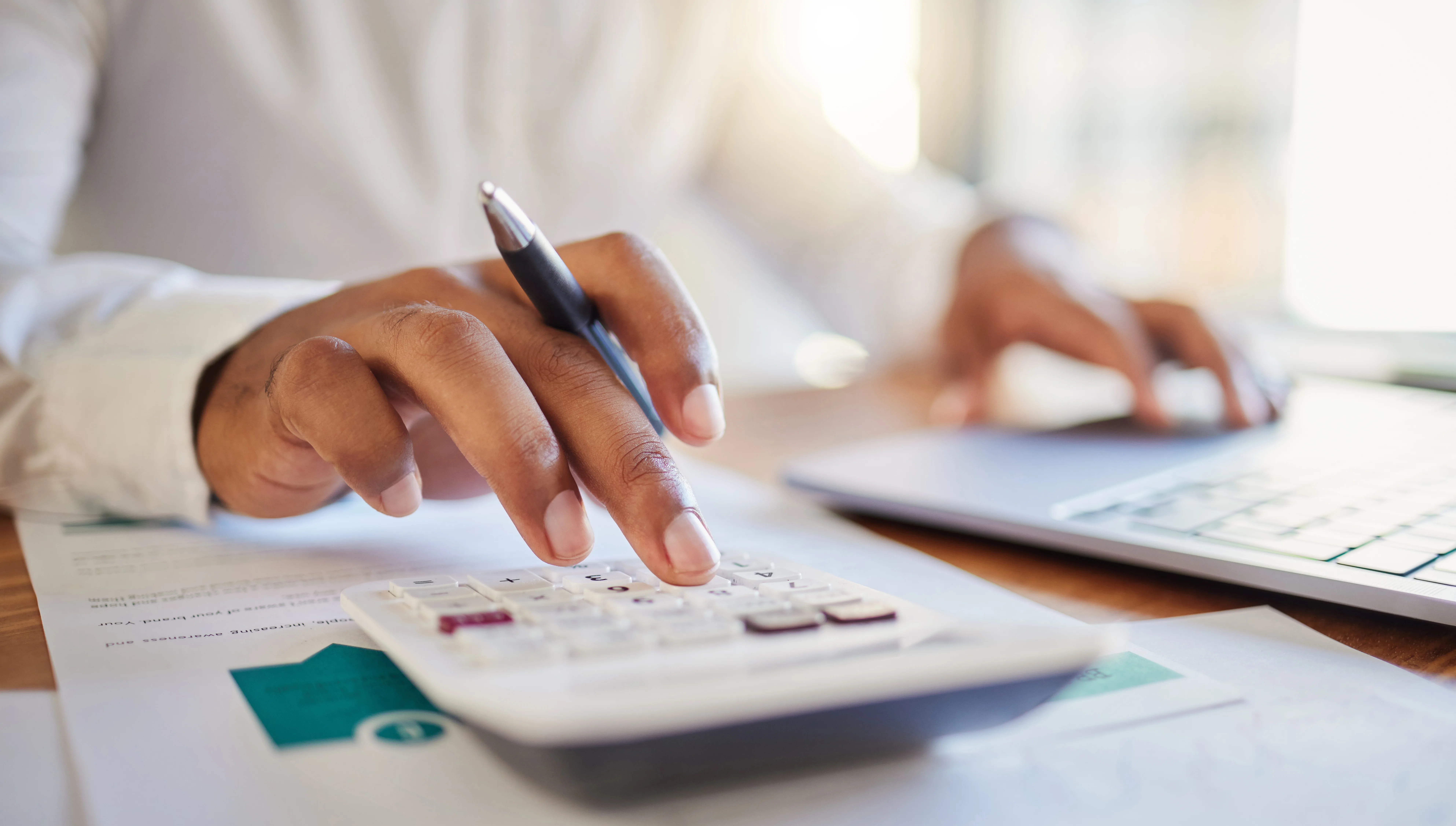 Finance, accounting and fintech, a man on a computer and calculator working out his business budget strategy. Businessman at his office desk, laptop, money management and financial investment online.